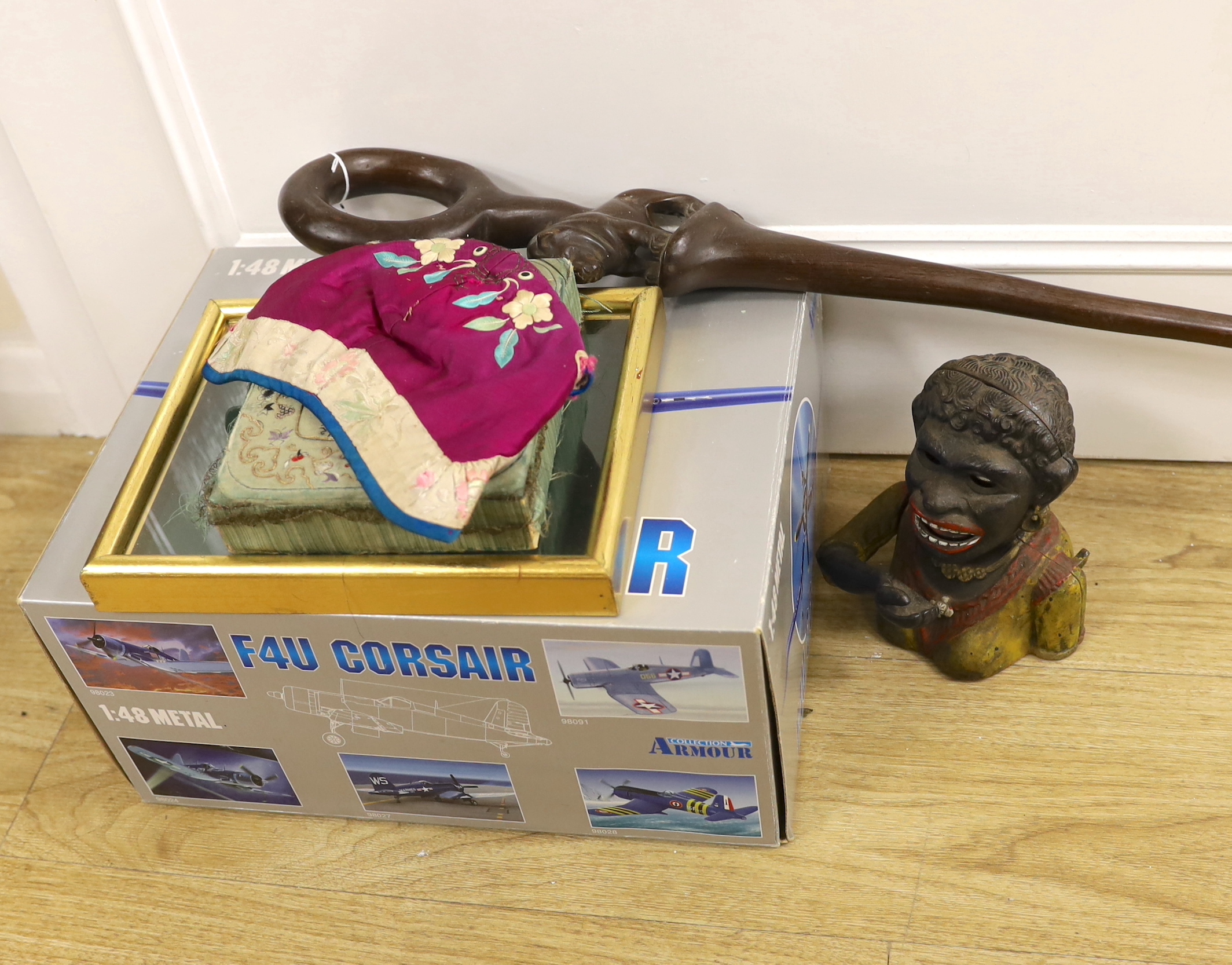 Six items, including an embroidered cap, embroidered box, framed gilt finals, a carved walking stick, a money box, and a diecast military aircraft